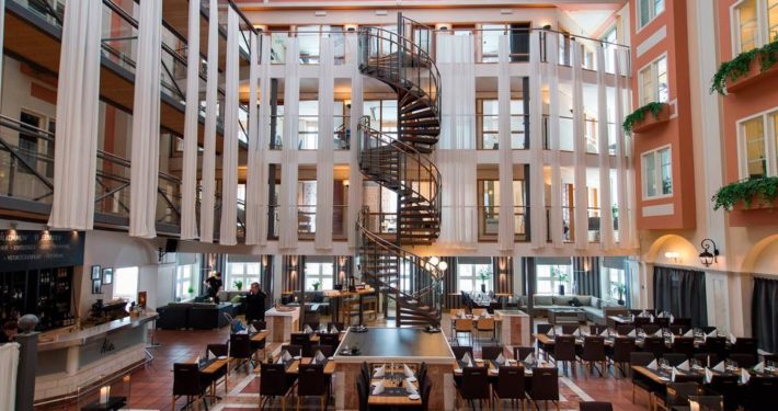 Restaurang med bord, stolar och en stor spiraltrappa i mitten